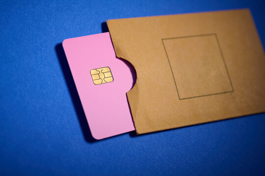 Close-up of a pink credit card in a small brown cardboard envelope.