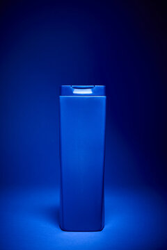 Closeup of a bottle of shampoo on a blue table.