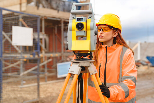 Surveyor in personal protective equipment (PPE) checks construction site with EDM Concept of construction engineering, site management,technology and women in construction industry