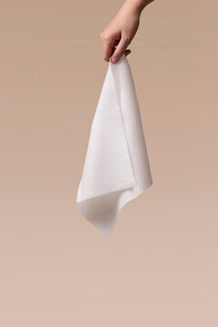 Hand holding a white textured disposable wipe