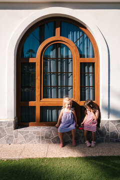 Little girls playing outside arched wooden window