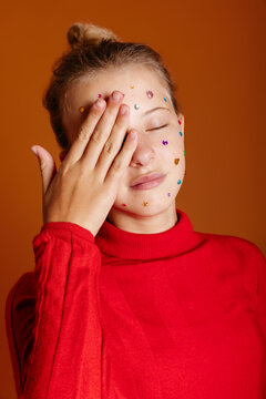 Teenager covering face with gems