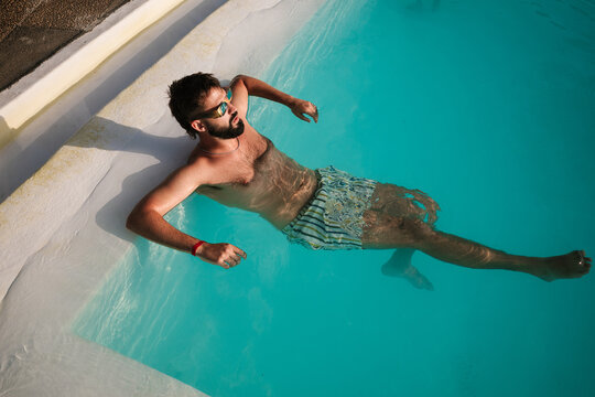 Man floating in swimming pool relaxing on summer vacation
