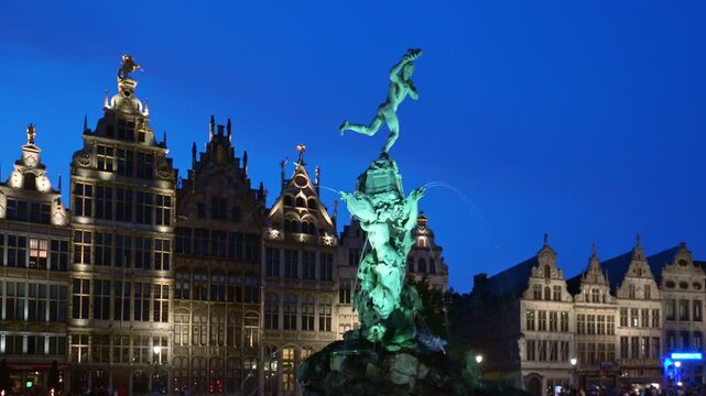 Lit fountain statue and guild houses at night in Antwerp