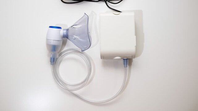 A nebulizer. Top view on the inhaler with a blue mask on the white background. Inhalation concept, lung diseases in the upper respiratory tract. High quality 4k footage.
