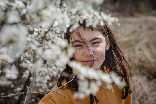 Young girl framed by white spring blossoms outdoors