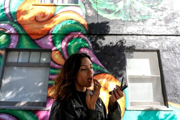 Woman applying lipstick outdoors mural © Rawpixel.com