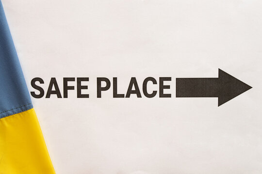 Safe Place text with a black arrow pointing toward a shelter on a white background next to the Ukrainian flag, symbolizing safety, protection