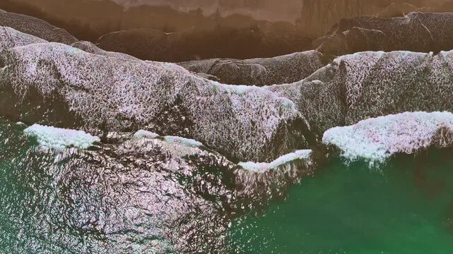 Parallel waves wash across a sandy Costa Rican beach. Green water, white foam and brown sand form overlapping bands along the shoreline.