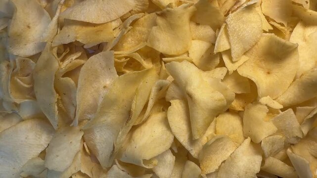 Shifting shadows on pile of crispy cassava chips, moving soft light over Manihot esculenta crisps texture, 4K video