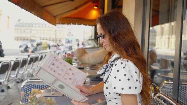 Smiling woman in sunglasses reading menu at Paris cafe