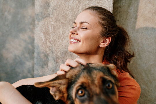 Happy young woman with closed eyes smiles while hugging her dog. Joyful moment of bonding and love between owner and pet, expressing care, friendship and emotional connection at home.