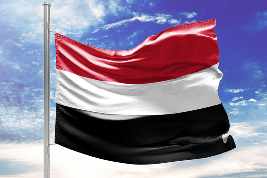 National Flag of Yemen Waving in the Wind against a Blue Sky