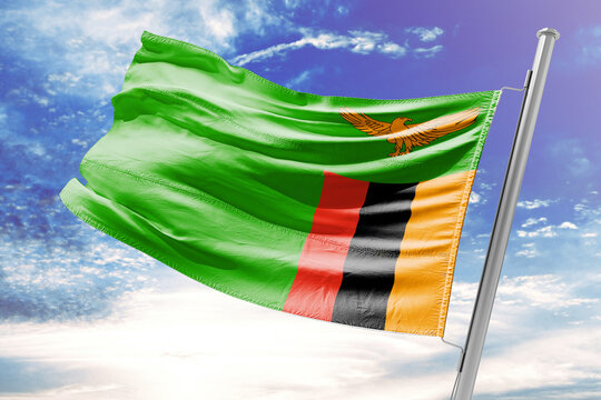National flag of Zambia waving against a blue sky with clouds