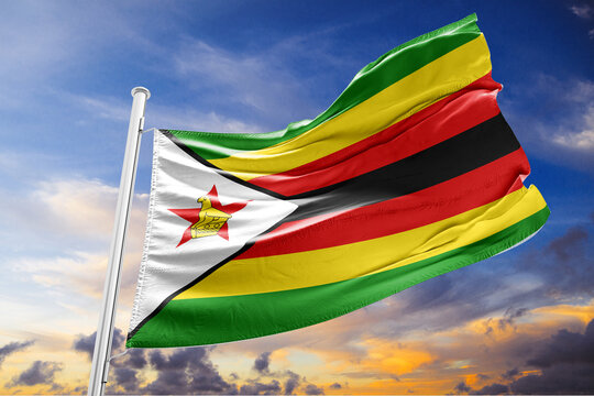 Zimbabwean flag waving proudly against a dramatic cloudy sunset sky