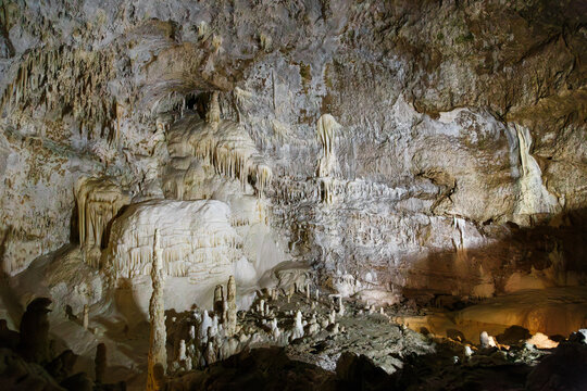Frasassi Caves, Marche, Italy. Cascate del Niagara or Niagara Falls flowstone and stalagmites in Abisso Ancona cave chamber. White frozen waterfall formation, underground background for geology