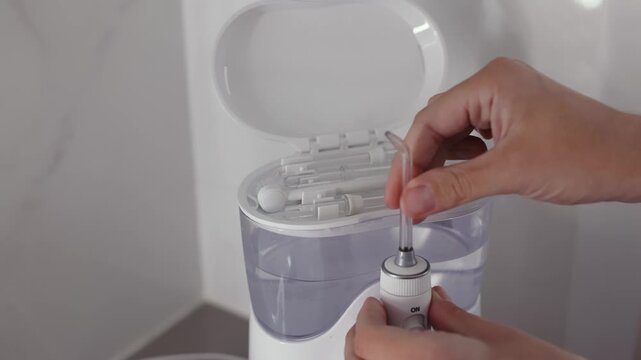 Woman&rsquo;s hands replacing a water flosser tip with a new attachment. Concept dental hygiene, oral care and home healthcare.