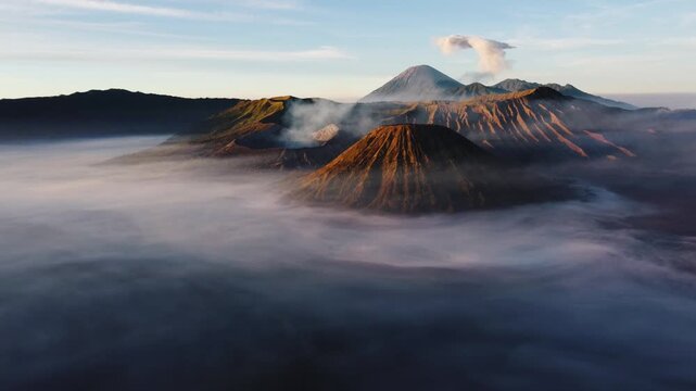 A bird's-eye view of the eruption of Bromo volcano at dawn in Bromo-Tengger-Semeru National Park, East Java, Indonesia. The caldera of Tengger volcano is hidden by clouds and fog. Dron.4K