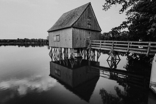 Monochrome stilt hut and bridge on pond