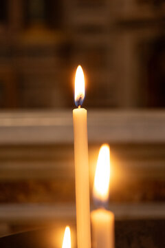 Rome, Italy - October 12, 2026: Close-up of lit candles glowing with warm flames inside a church in Rome, Italy