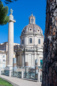 Trajan's Column and the dome of Santissimo Nome di Maria church framed by a pine trunk in Rome, Italy