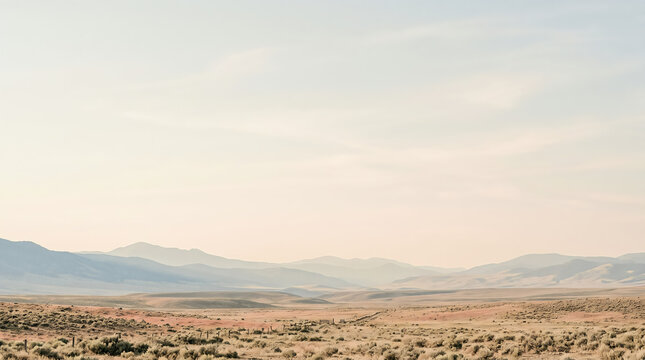 Vast desert landscape with rolling mountains under a soft hazy morning sky