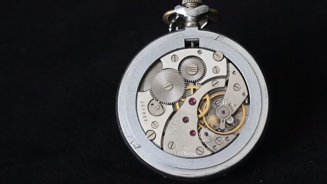 Close up of vintage pocket watch internal brass mechanism gears on black background