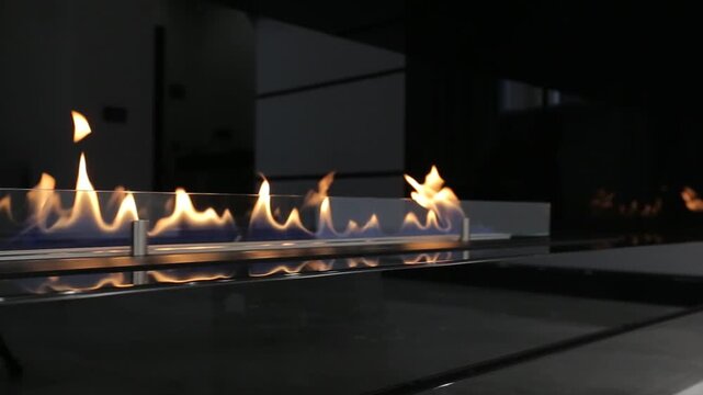 Camera panning left on modern linear bioethanol fireplace with burning blue yellow flame