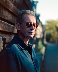 Vintage film portrait of a man in sunglasses beside a brick wall © Jorge Elizaquibel