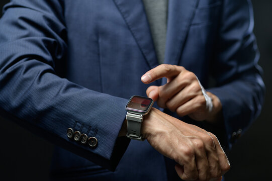 Businessman Checking Time on Smartwatch While Using Smartphone in Office