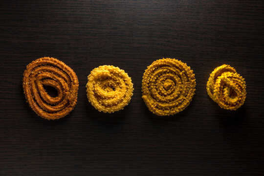 Popular traditional Indian snack - Chakli or Murukku. Various types of deep fried Chaklies arranged in a row, shot from above. Indian authentic food and savory.
