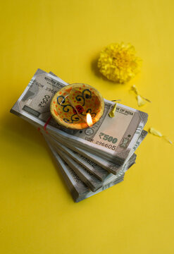 Five hundred Indian rupee currency notes is being worshipped as a custom during festival of Diwali. An earthen lamp and marigold flowers with Indian currency notes. View from top.