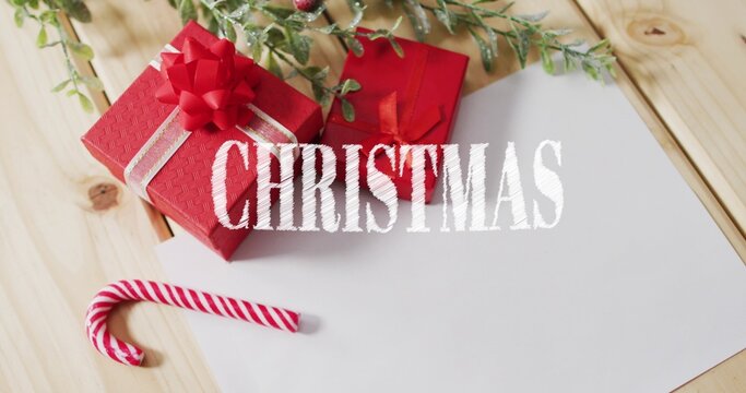 Displaying red gift box with bow and silver ribbon on wooden tabletop, card, candy cane, foliage