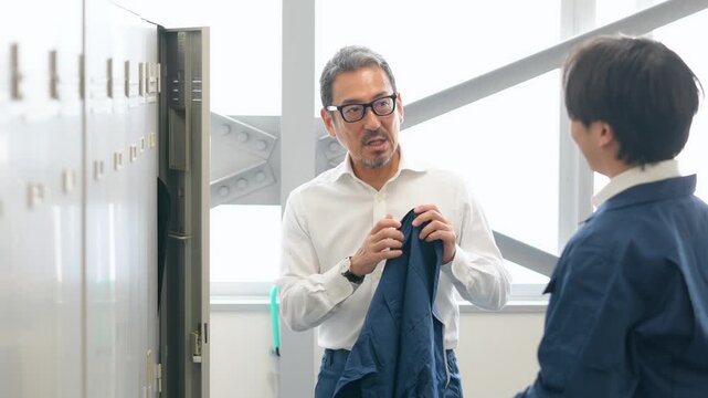 ロッカールームで着替える作業員。工場、作業服、仕事、会話、退勤、出勤、始業、更衣室、準備、エンジニア