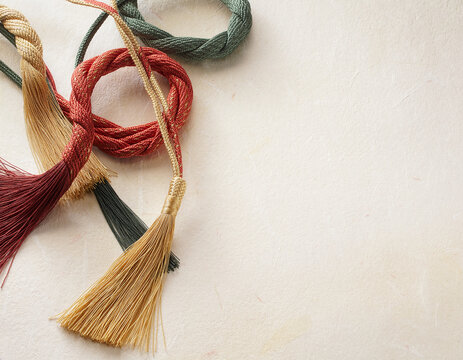 Red, gold and green braided silk cords with tassels on Japanese washi paper