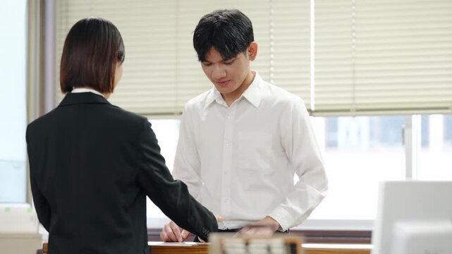 窓口で会話するアジア人男性。役所、手続き、ビザ、移住、在留カード、申請、笑顔、技能実習生、相談、受付