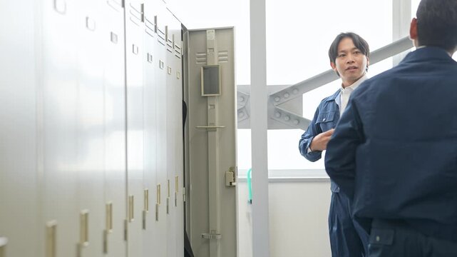 ロッカールームで着替える作業員。工場、作業服、仕事、会話、退勤、出勤、始業、更衣室、準備、エンジニア