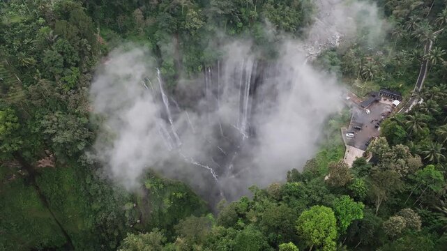 Aerial Drone Slowly Orbiting Misty Tumpak Sewu Waterfall from Above on an Overcast Day in East Java, Indonesia