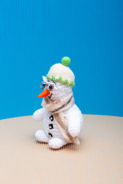 Snowman knitted from yarn, set against a colorful background