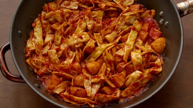 A rotating pan of string beans with tomato passata, potatoes, and plenty of olive oil. Greek fasolakia lathera dish made with Merveille de Venice beans.