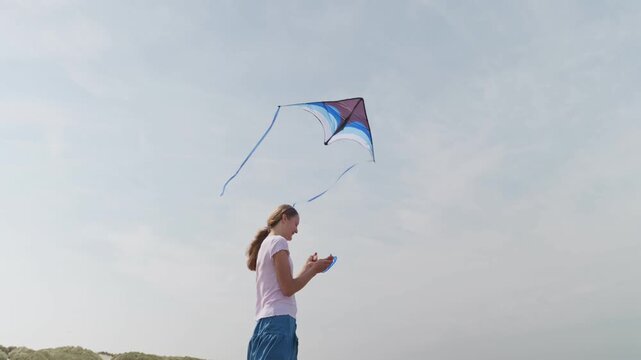 A girl is standing with a kite view from below the sky in the background