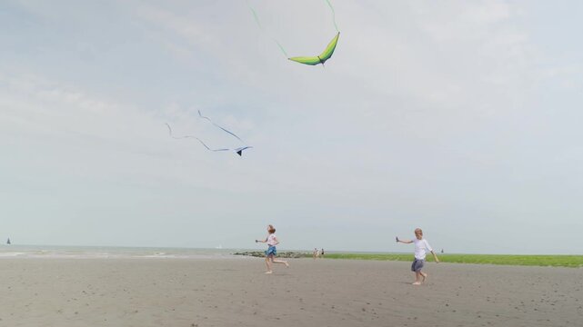 Happy boy and girl running barefoot with kites on a sandy beach children at a seaside resort