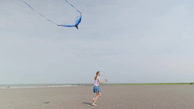 A girl is smiling with a kite on the beach slow motion runs along the seashore