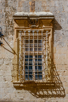Limestone Window Frame Featuring Decorative White Metal Security Bar Grille and Carved Shell Ornament