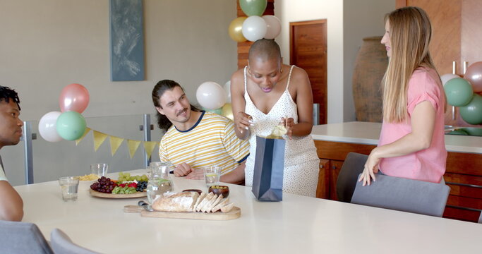 At party, Friends hugging warmly at home while another friend watches with curiosity