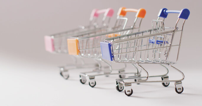 Three empty shopping trollies on seamless grey background