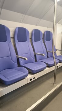 Modern comfortable purple seats inside a public transport train carriage, interior design with power sockets and handrails, commuter travel and public transit concept for stock 