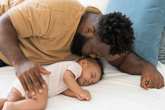 African American father kissing on head of newborn baby infant with kidly and love, adorable smiling mixed race baby, fatherhood moments, love and parenting care at home