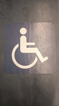 White wheelchair accessibility symbol sign on blue floor background, handicap priority sign in public transport for microstock photography.