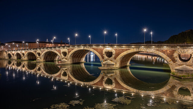 Toulouse, France - September 20, 2026: The illuminated Pont Neuf (New Bridge) with perfect reflections of its arches on the Garonne at night.